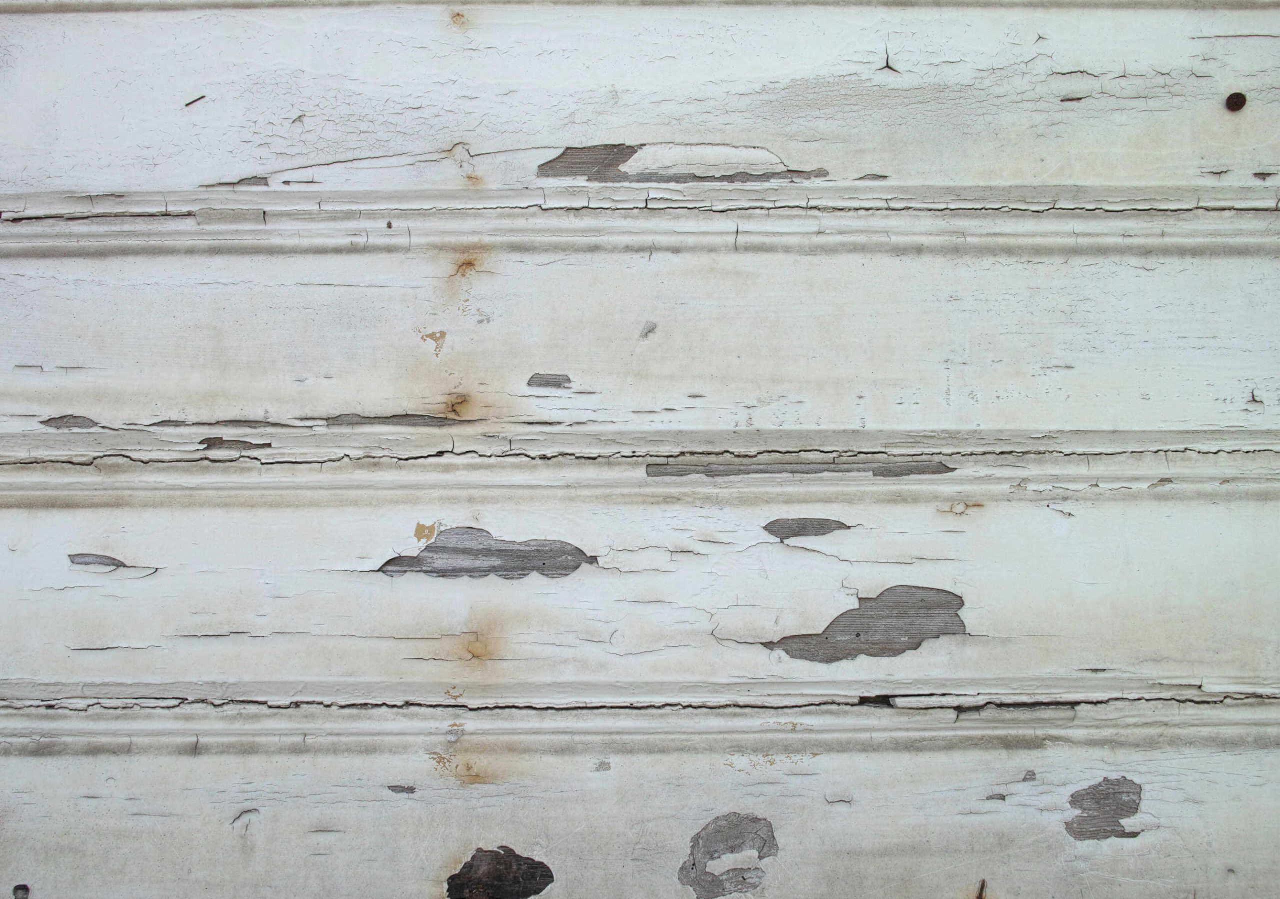 Rotted wood siding on a house exterior in need of repair before painting.