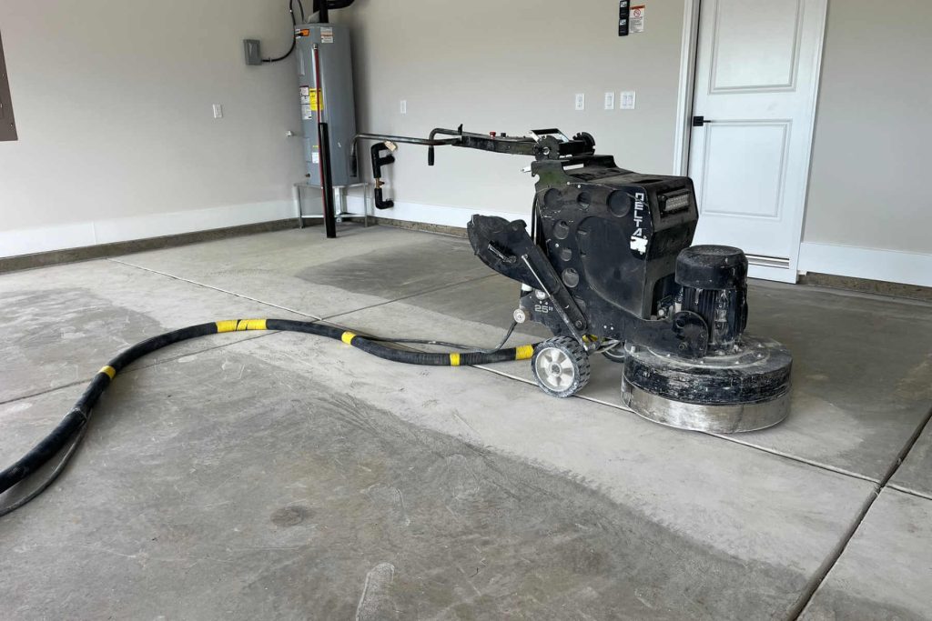 A garage floor getting grinded in preparation for an epoxy coating.