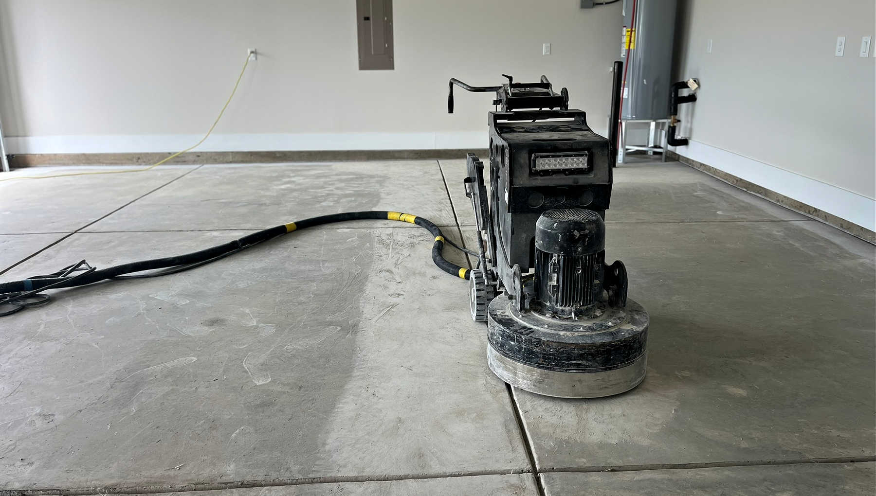 A garage floor being grinded down in preparation for an epoxy floor coating.