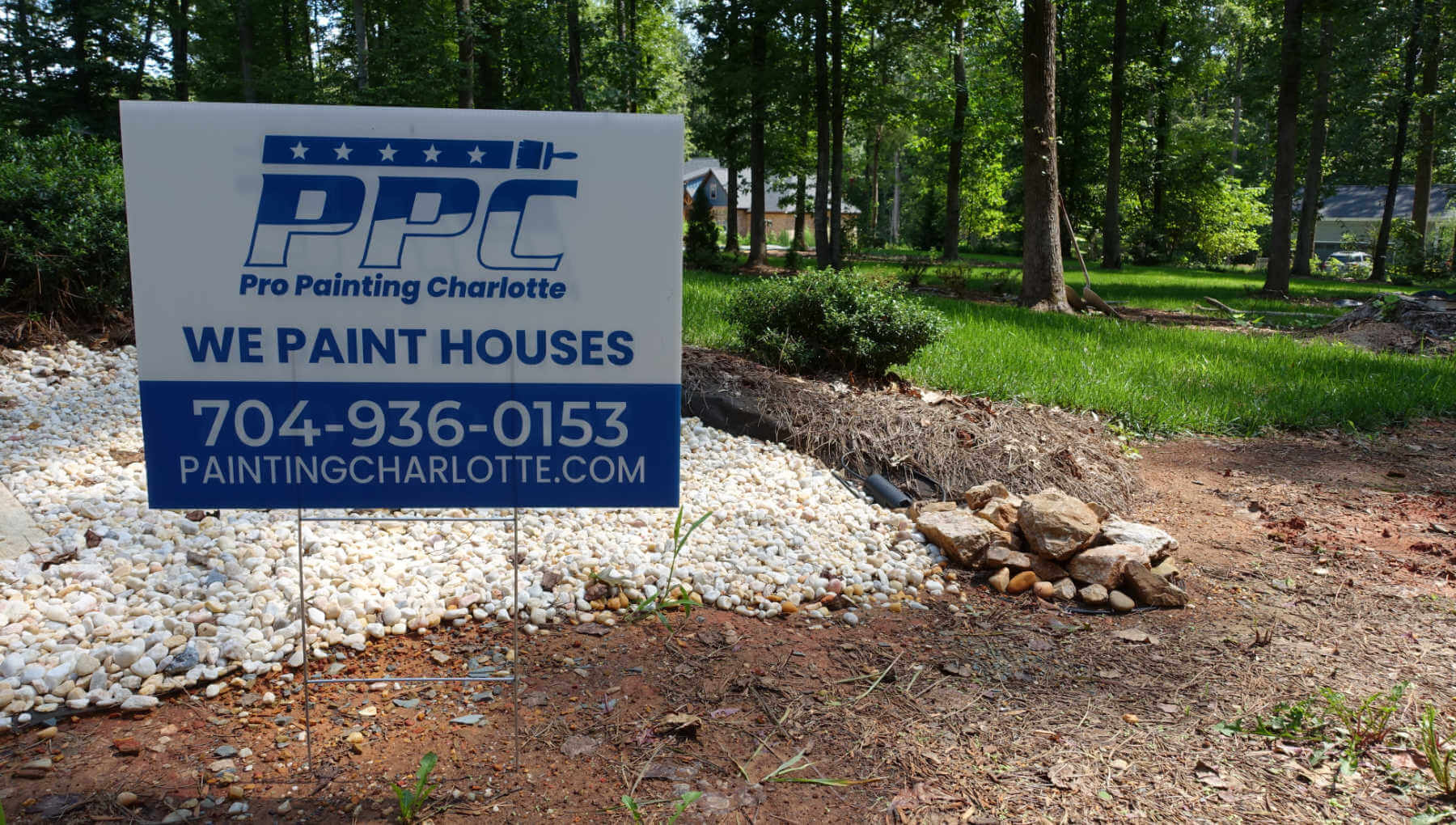 A business sign for pro painting charlotte in a customers front yard.