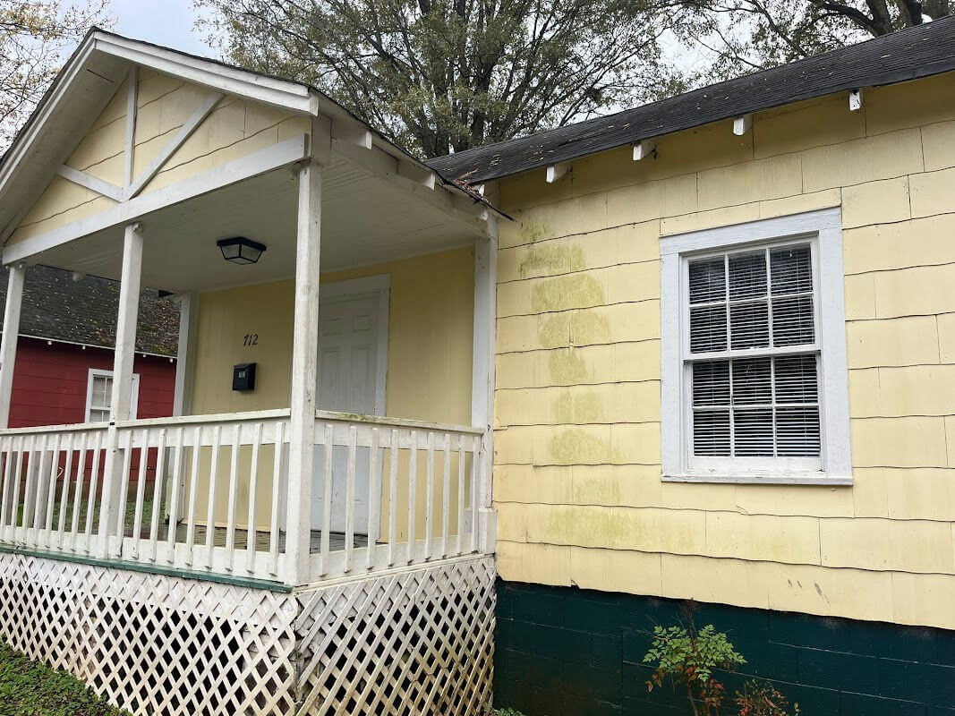 A dirty house with green on the siding in need of pressure washing.